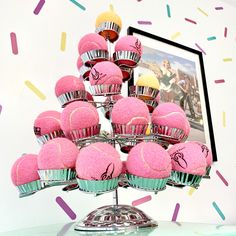 there are many pink cupcakes that are on the cake stand with sprinkles