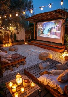 an outdoor movie is set up in the backyard with candles and lights on the ground