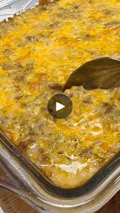 a casserole dish with cheese and meat in it being spooned into the casserole