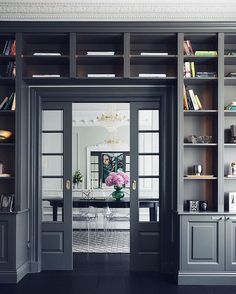 an open door leading to a dining room with built - in bookshelves and chairs