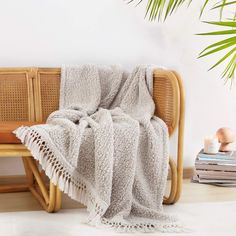 a wooden bench with a blanket on top of it next to a potted plant