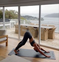 a woman is doing yoga in front of a large glass door with an ocean view