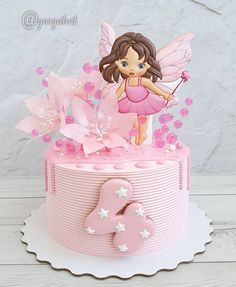 a pink birthday cake with a fairy on top