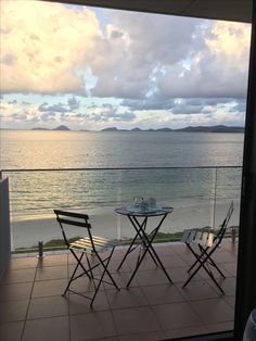 two chairs and a table on a balcony overlooking the ocean