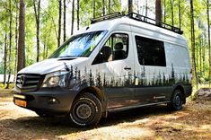 a van parked in the woods with trees painted on it