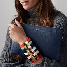 a woman is holding a blue purse and wearing bracelets