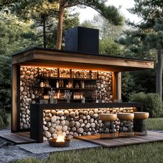 an outdoor bar made out of rocks and lit up with candles on the outside, surrounded by trees