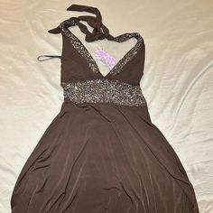 a brown dress with sequins on it laying on top of a white sheet