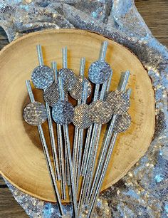 there are many metal pins in the shape of hearts on a wooden plate with silver sequins