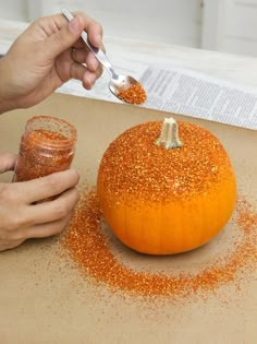 someone is decorating an orange pumpkin with glitter