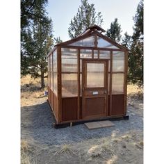 a small wooden outhouse sitting in the middle of a field