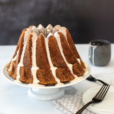 a bundt cake sitting on top of a white plate next to a fork and cup