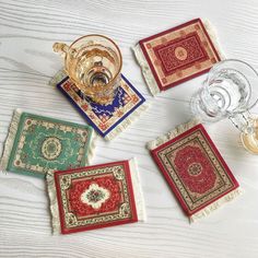 four coasters with different designs on them and wine glasses in the middle one is empty