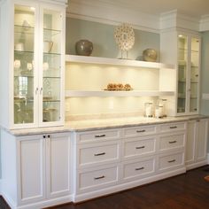 a kitchen with white cabinets and marble counter tops