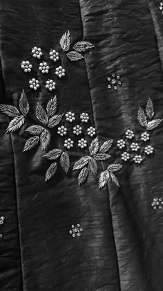 black and white photograph of embroidered fabric with flowers on it's side, closeup