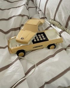 a toy car connected to a phone on top of a white and brown striped bed