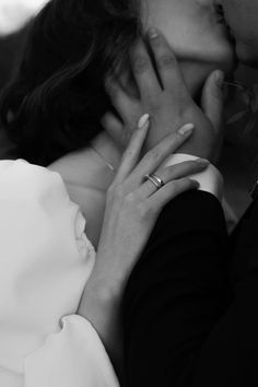 a man and woman kissing each other with their hands on the forehead, in black and white