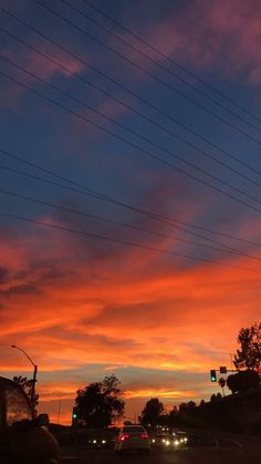 the sun is setting behind power lines and cars are driving down the street at night