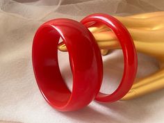 "These two bangle bracelets are made of bright red solid color Bakelite/Catalin (phenolic resin). They have been simichrome tested and positively identified as genuine Bakelite/Catalin.  Thick bangle: 3 1/8\" x 1 1/16\" Thin bangle: 3 1/8\" x 7/16\" Both have small signs of wear and age as is normal for vintage plastics, but are generally in very good condition. The larger bangle has a small chip on the interior edge." Red Solid Color, Boho Art Deco, Red Bangles, Fashion Moodboard, Art Deco Bracelet, Bangle Bracelet Set, Bracelets Set, Vintage Bakelite, Mood Board Fashion