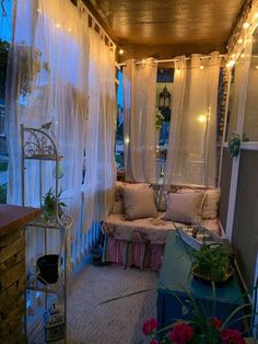 an outdoor covered porch with curtains and lights