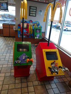 two mcdonald's play tables in the middle of a tiled floored area with large windows