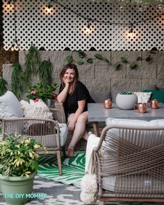 a woman sitting on top of a chair next to a table with potted plants