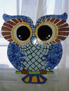 an owl statue sitting on top of a window sill in front of a curtain