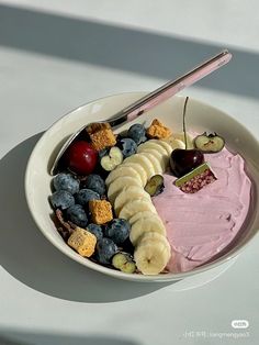 a white bowl filled with fruit and crackers on top of a table next to a spoon