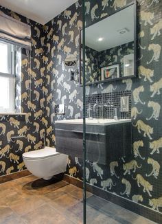 a bathroom with black and gold wallpaper, white toilet and sink