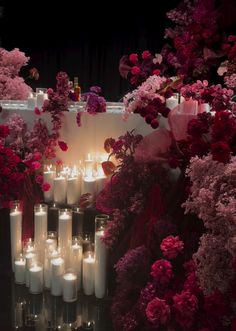 many candles are lit in front of flowers