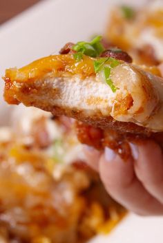 a person holding up a piece of pizza with cheese and sauce on it, in front of other food items