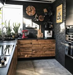 a kitchen with black brick walls and wooden cabinetry, two large clocks on the wall