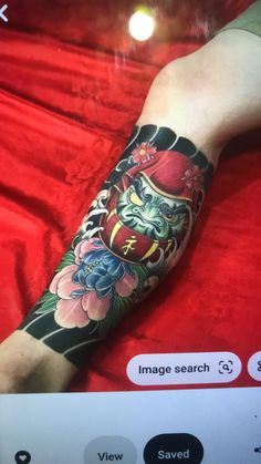 a person with a dragon tattoo on their arm and leg, sitting on a red blanket