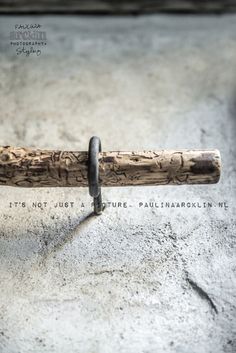 a close up of a wooden baseball bat on a cement surface with words written below it