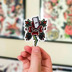 a person holding up a sticker with a knife in it's center and flowers on the back