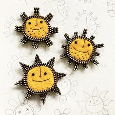 three sun brooches are sitting on a table next to each other and one has a smiling face