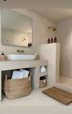 a bathroom with a sink, mirror and bathtub next to a wooden mat on the floor