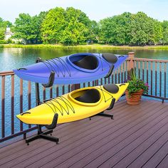 two kayaks sitting on top of a wooden deck next to a lake