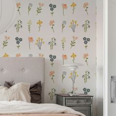 a bed sitting next to a wall with flowers on it