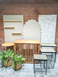 three chairs and two tables in front of a brick wall with planters on it