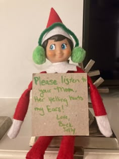 an elf is holding a sign that says please listen to your mom, he's really