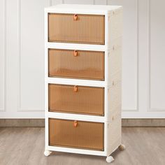 a white cabinet with three baskets on the front and four drawers in the back, against a wooden floor