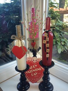 two wine bottles are sitting next to each other in front of a window with a valentine's day sign on it