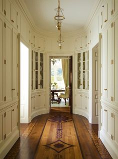 a hallway with white walls and wooden flooring next to an open door that leads to another room