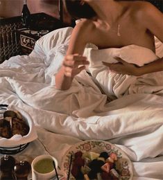 a woman sitting in bed with food on the table