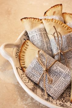 several pastries are wrapped in newspaper on a plate