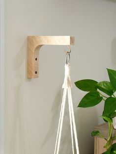 a white macrame hanging from a hook on a wall next to a potted plant