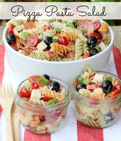 pasta salad with tomatoes, olives, and other vegetables in small glass containers on a red and white striped tablecloth