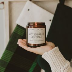 a person holding a jar of gingerbread and space candle in their left hand, next to some stockings