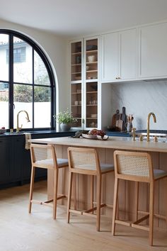 a kitchen with an arched window and two stools in front of the counter top